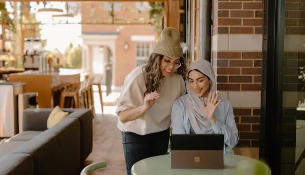 A content creator filming a how-to video tutorial with a laptop and a coffee shop setting.